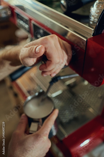 The hands of barista bartenders make an espresso of coffee on machine in cafe bar. Closeup.