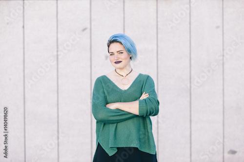 Photos portrait of a teen androgynous woman with blue dyed hair isolated on the street