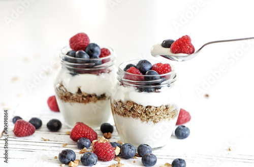 Yogurt with bluberry and raspberry in the glass jars with berries around