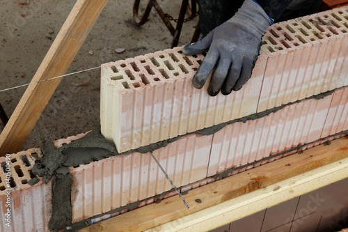 bricklayers hand with glove puts a stone in row