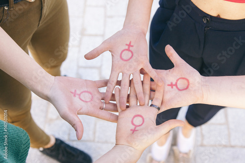close up of small group of women with the symbol of feminism written on her hands