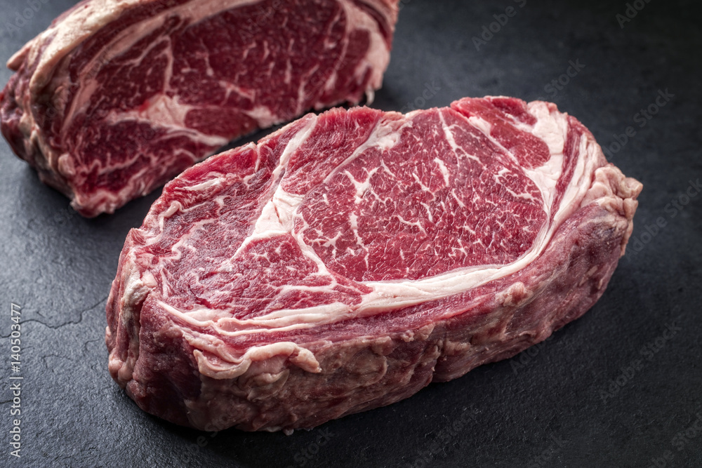 Two raw dry aged Wagyu Rib Eye Steaks on a slate Two raw dry aged Wagyu Rib Eye Steaks on a slate