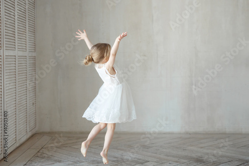 A little girl dancing in a room in a beautiful dress