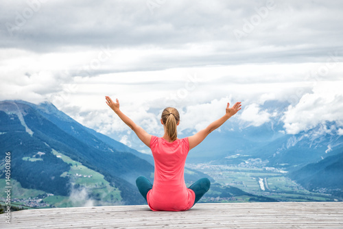 young woman meditate on top of the mountain