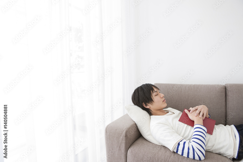 Young Man Sleeping on Sofa with Book Young Man Sleeping on Sofa with Book