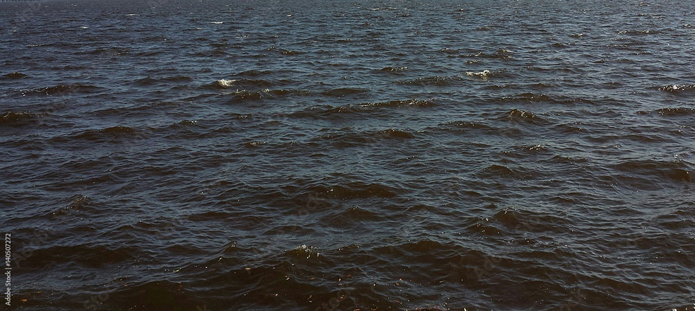 Dark river water surface with soft waves as a background Dark river water surface with soft waves as a background