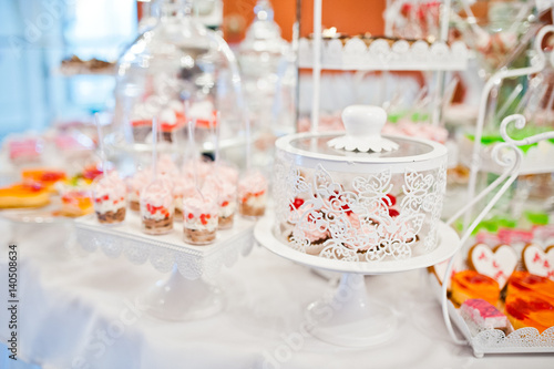 Different sweets and cupcakes at catering wedding reception table.