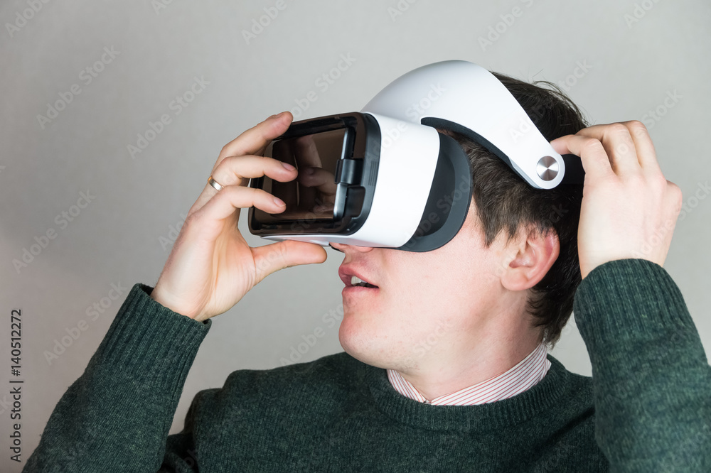 Wearing virtual reality glasses. Excited male person uses vr headset for the first time and looks amused and astonished Wearing virtual reality glasses. Excited male person uses vr headset for the first time and looks amused and astonished