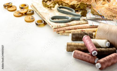 Accessories for sewing and cutting lie on a white table. Space for an object.