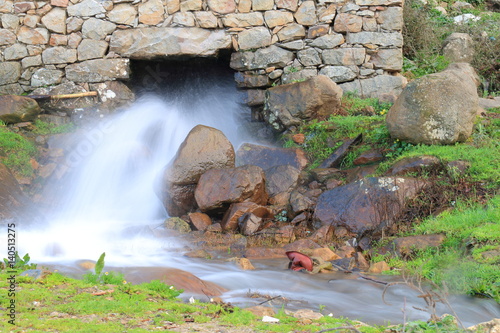Water stream coming out of a traditional old water mill in full activity
