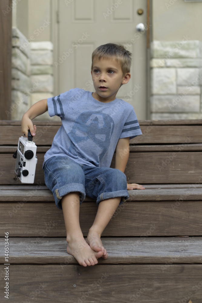 Naklejka premium Stylish boy in jeans sitting on stairs with portable radio