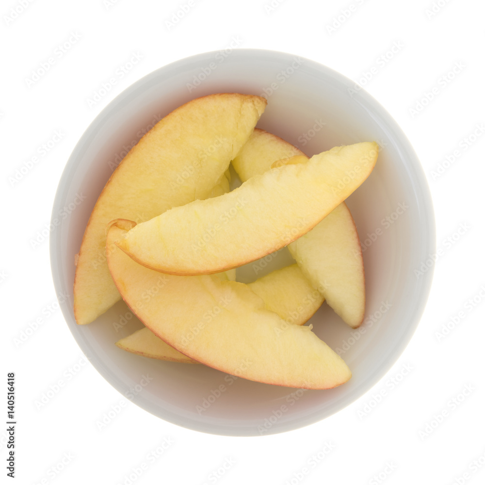 Red apple slices in a small white bowl top view.