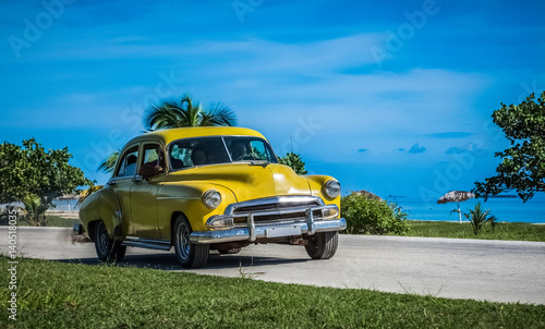 Amerikanischer gelber Oldtimer fährt auf der Küstenstraße nach Santa Clara Kuba - Serie Kuba Reportage