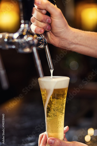 Bartender pouring the fresh beer in pub barman hand at beer tap pouring a draught lager beer beer from the tap Filling glass with beer fresh beer pub.Bar.Restaurant.European bar.American bar.