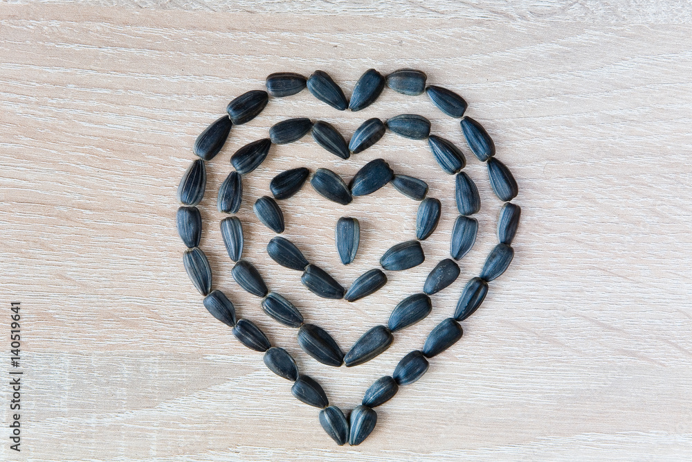 A mosaic in the shape of a heart symbol composed of sunflower seeds.