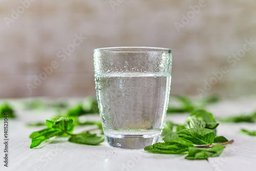 Glass of fresh cold water with mint on table