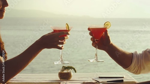 romantic dinner on the beach in luxury restaurant, couple drinking tropical cocktails at sunset