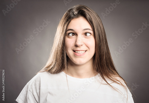 happy young girl squinting on a gray background