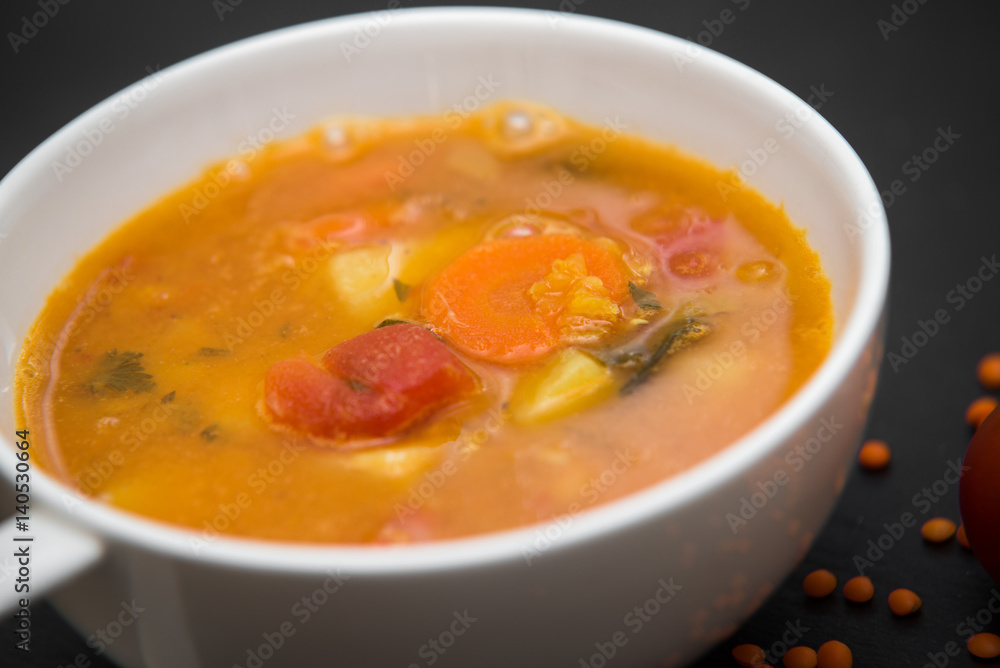 close up on soup with tomato, lentil and potato, rustical background, top view close up on soup with tomato, lentil and potato, rustical background, top view