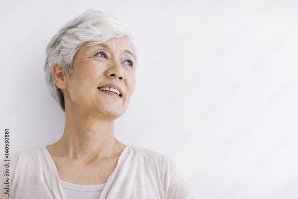 Mature woman smiling and looking away, white background, copy space Mature woman smiling and looking away, white background, copy space