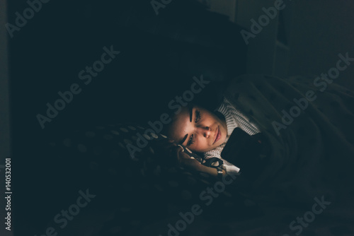 Fotografía Young beautiful woman using smart phone at night in bed - technology, social net