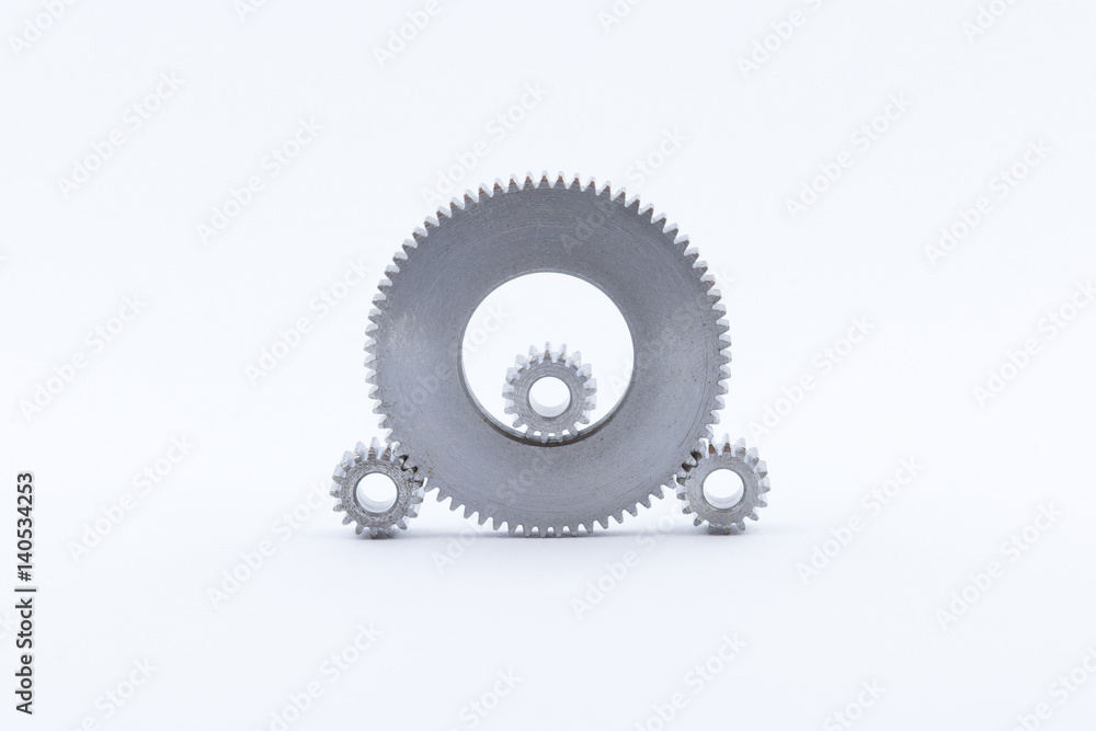 Isolated metal pinions gear. The iron gear on a white background. Pinions in the gearbox. Parts to the gear mechanism. Sprockets to clockwork. Shiny gear ready for assembly. Isolated metal pinions gear. The iron gear on a white background. Pinions in the gearbox. Parts to the gear mechanism. Sprockets to clockwork. Shiny gear ready for assembly.