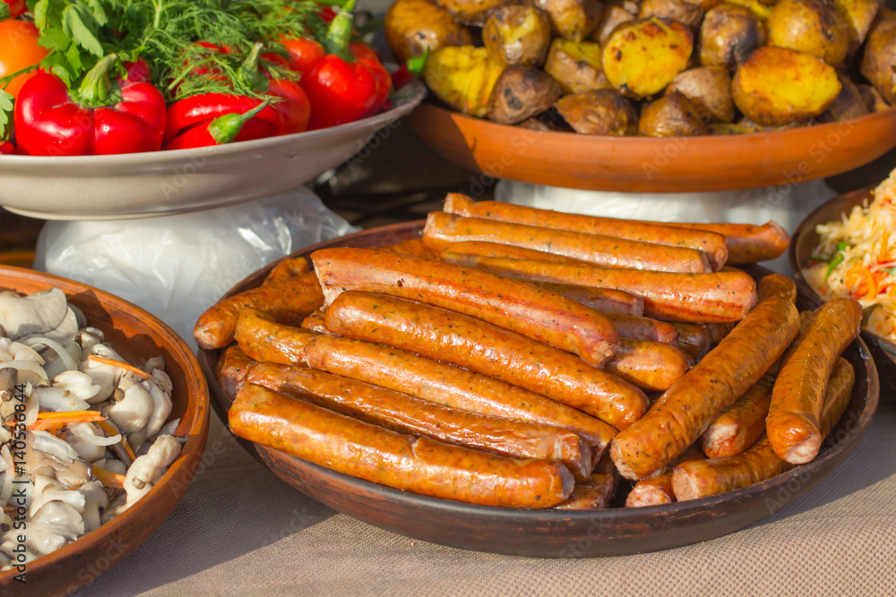 Grilled sausages on  plate, fried potatoes and red pepper on the table