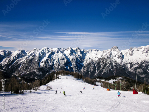 People ski in the Alps and the beautiful mountain in the background.