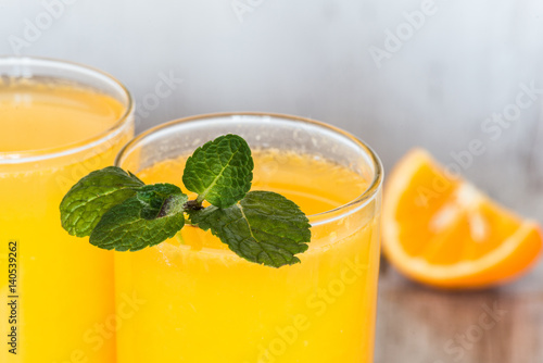 orange juice with closeup mint in glasses at light background
