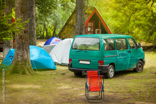Camper van in the camping with tents and trees