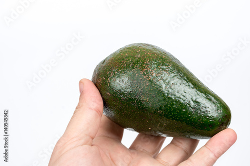 Whole green avocado in the hand over white background
