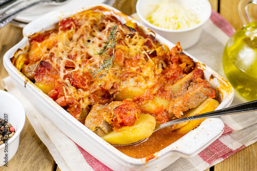 Baked potato gratin with pork meat and tomatoes