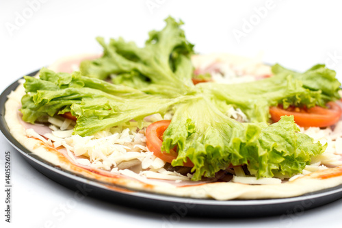Preparing pizza with lettuce and tomato over white background