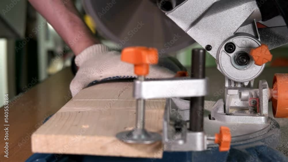 The worker cuts a wooden block on the machine The worker cuts a wooden block on the machine