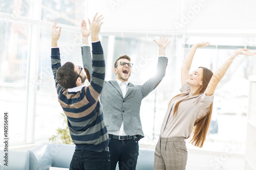 Fototapeta concept of victory - the jubilant business team standing in a circle, hands up in rejoice success