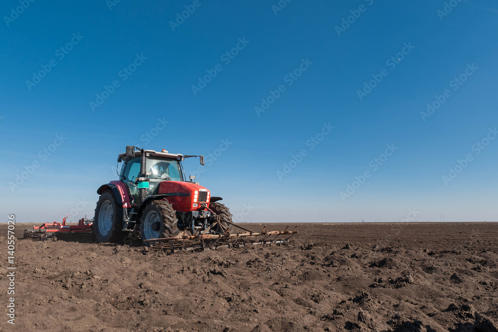 Farmer in tractor preparing land with seedbed cultivator in spring Farmer in tractor preparing land with seedbed cultivator in spring
