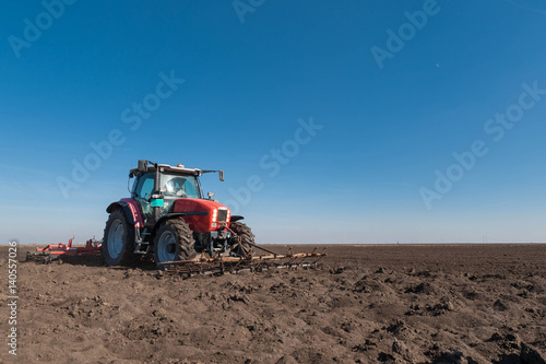 Farmer in tractor preparing land with seedbed cultivator in spring