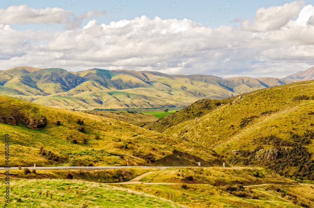 Naklejka premium View of barren hills under clouds from Lindis Pass in Central Otago on the South island of New Zealand