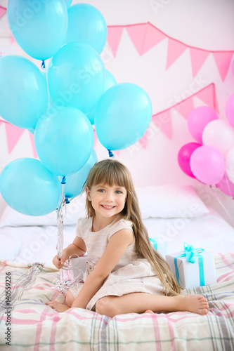 Cute girl with balloons sit...