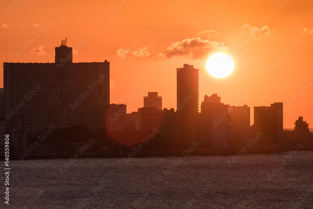 The city of Havana at sunset with the sun setting over seaside highrise buildings