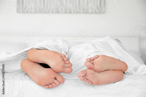 Feet of young cute couple together in bed