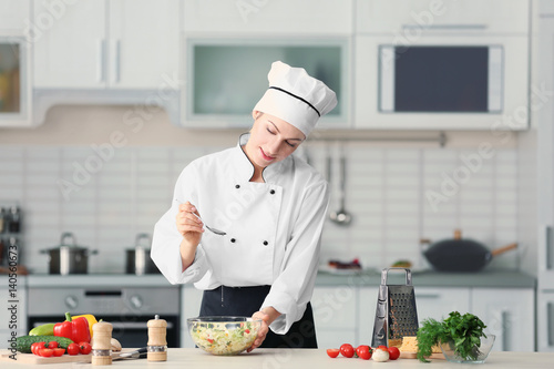 Female chef adding oil to v...