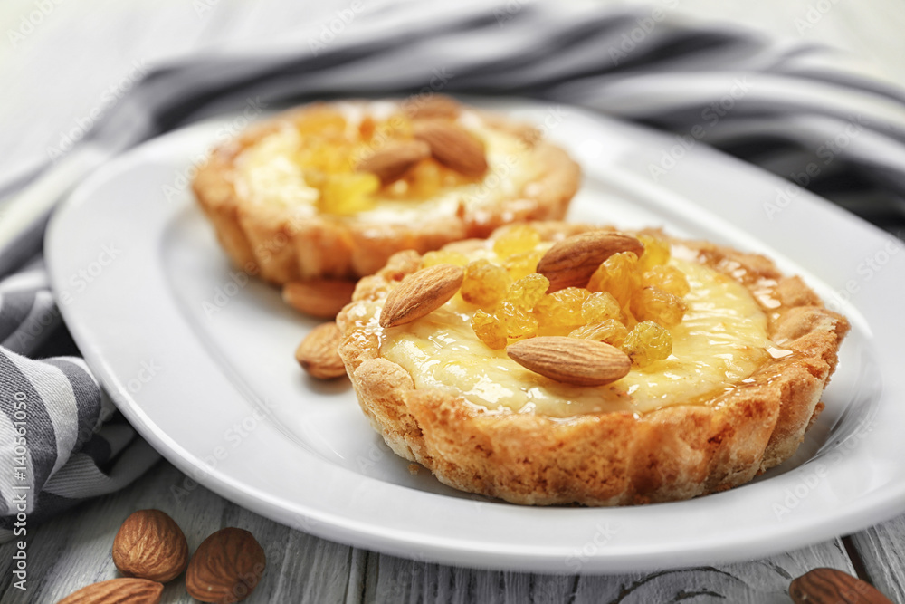 Delicious crispy tarts with almond and raisins on white plate, closeup Delicious crispy tarts with almond and raisins on white plate, closeup