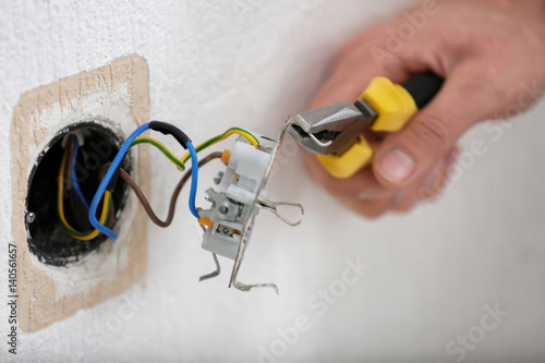 Hands of electrician installing socket, closeup