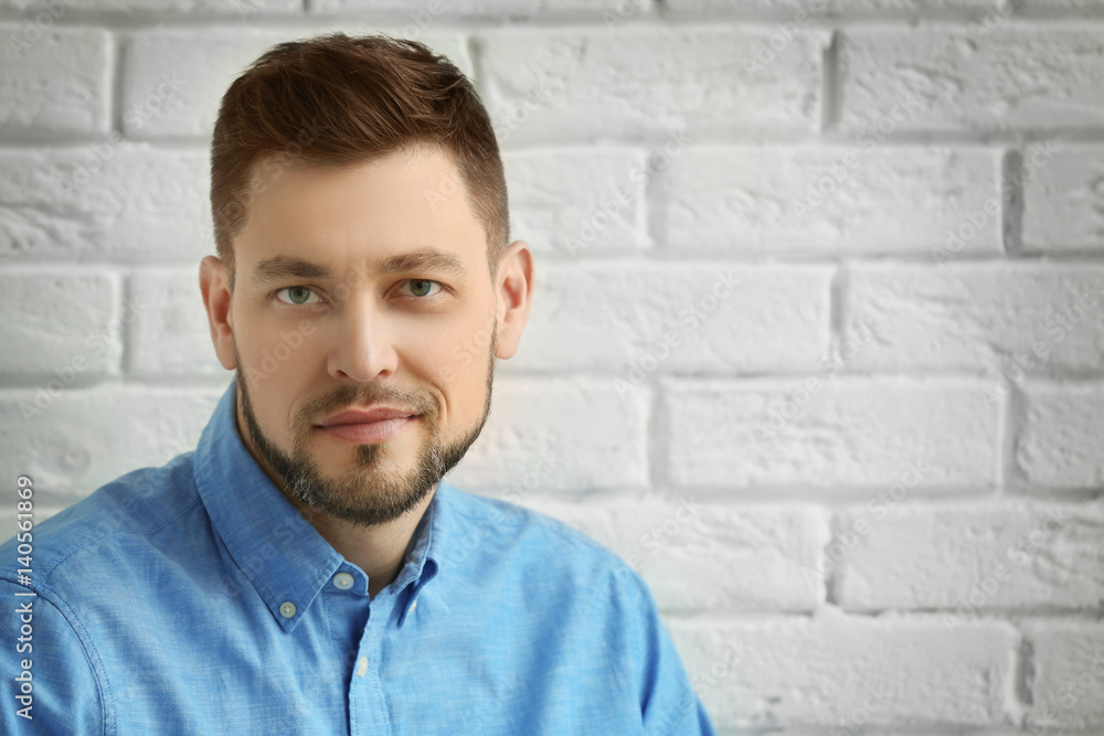 Handsome young man posing on white brick wall background