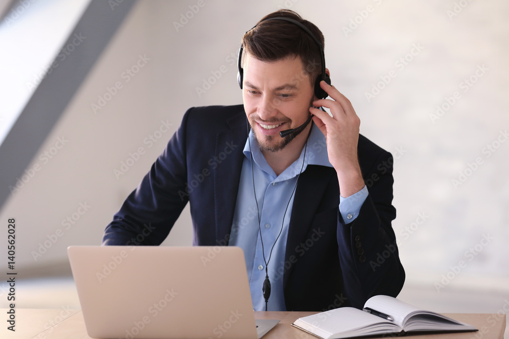 Young man with headset and laptop working in office Young man with headset and laptop working in office