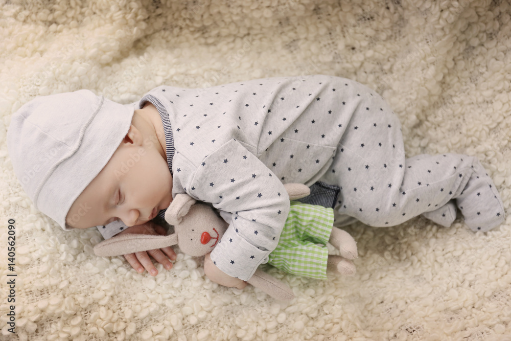 Cute little baby with bunny toy sleeping on plaid at home Cute little baby with bunny toy sleeping on plaid at home