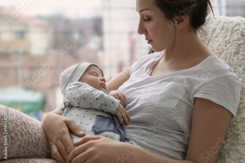 Young woman with cute sleeping baby at home