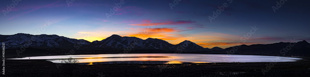 Fototapeta premium Desert lake, flooded playa at Sunset with mountain ranges and colorful clouds. White Lake, Cold Springs, Nevada