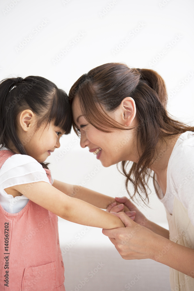 Mother and daughter holding hands and touching forehead Mother and daughter holding hands and touching forehead